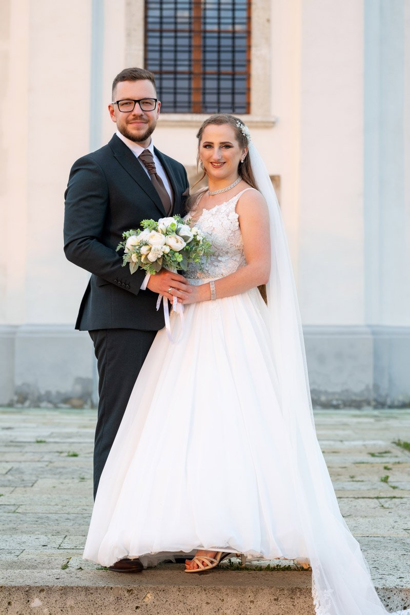 Melinda és Béla elegáns esküvői portréja a templom előtt
